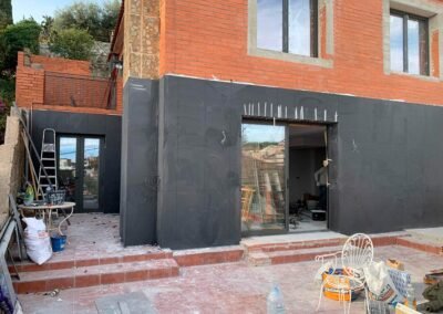 Obra de rehabilitación de fachada con gres porcelánico oscuro y aislamiento térmico en Santa Coloma