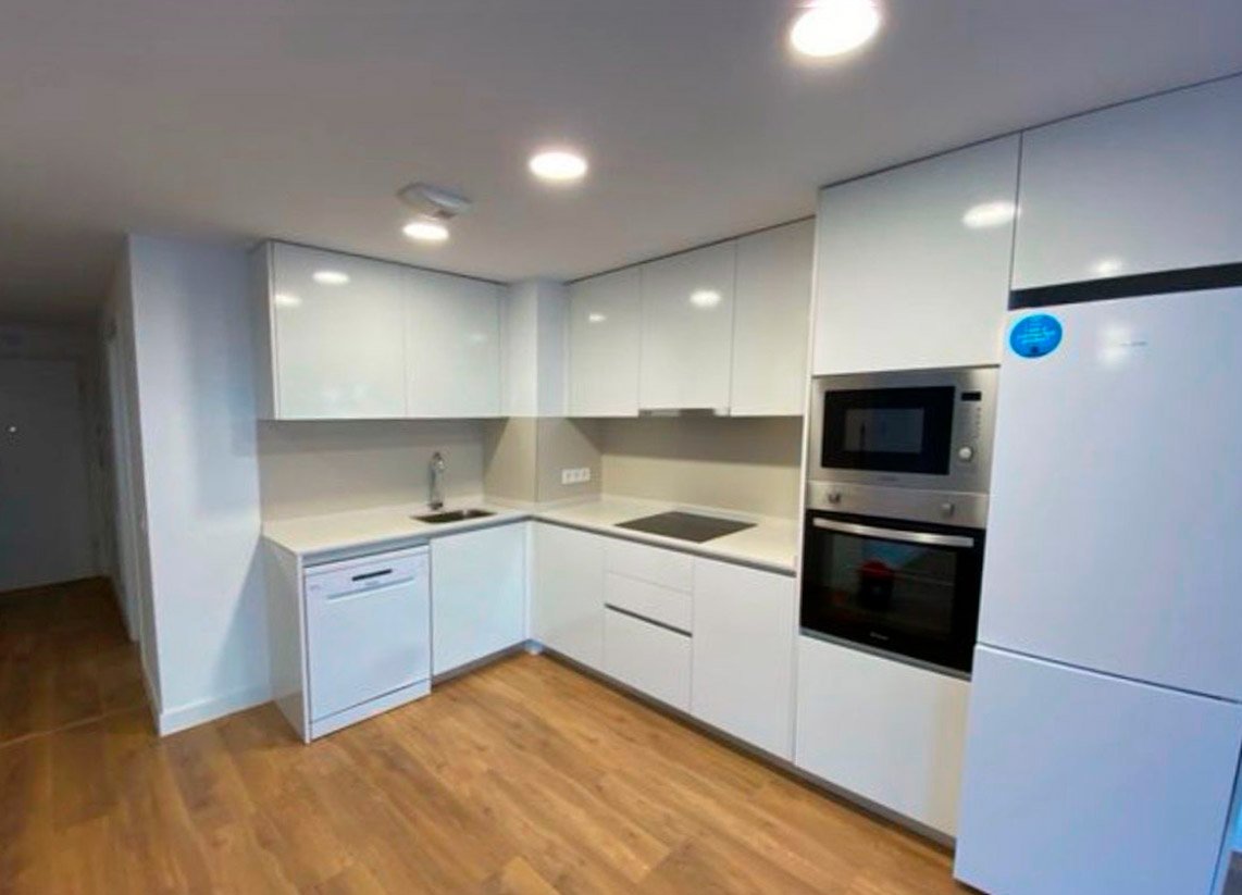 Encimera de cuarzo compacto blanco en cocina moderna reformada sin tiradores